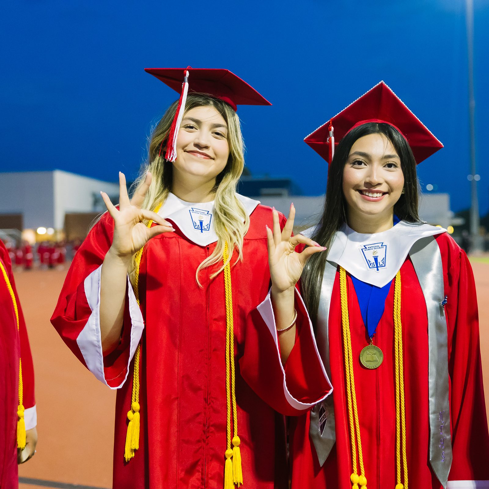 Four HCISD graduates in caps and gowns on the field at Boggus Stadium